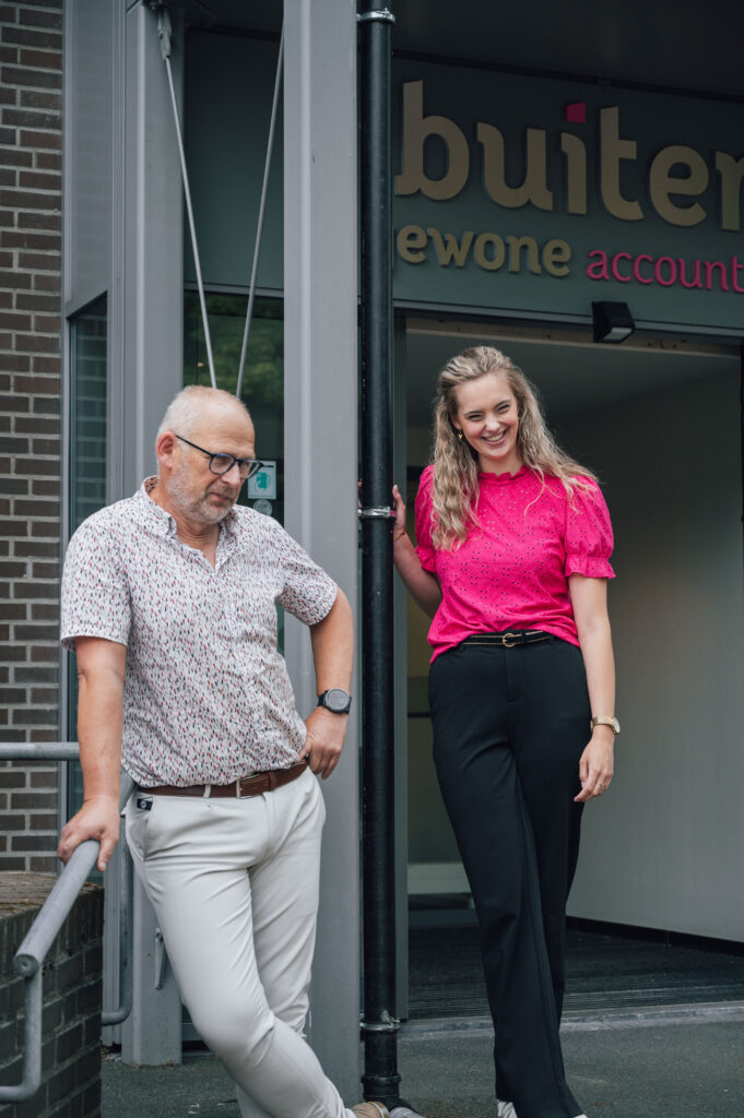 twee collega's (man en jonge vrouw) staan voor het kantoorpand
