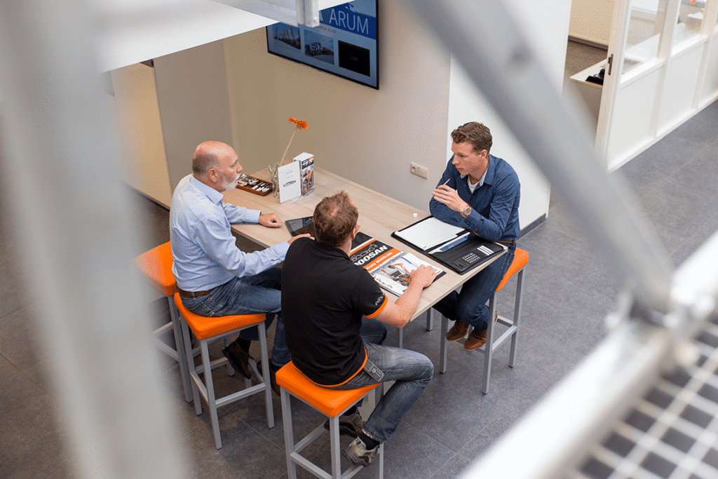 drie mannen zitten aan een tafel en hebben zakelijk overleg