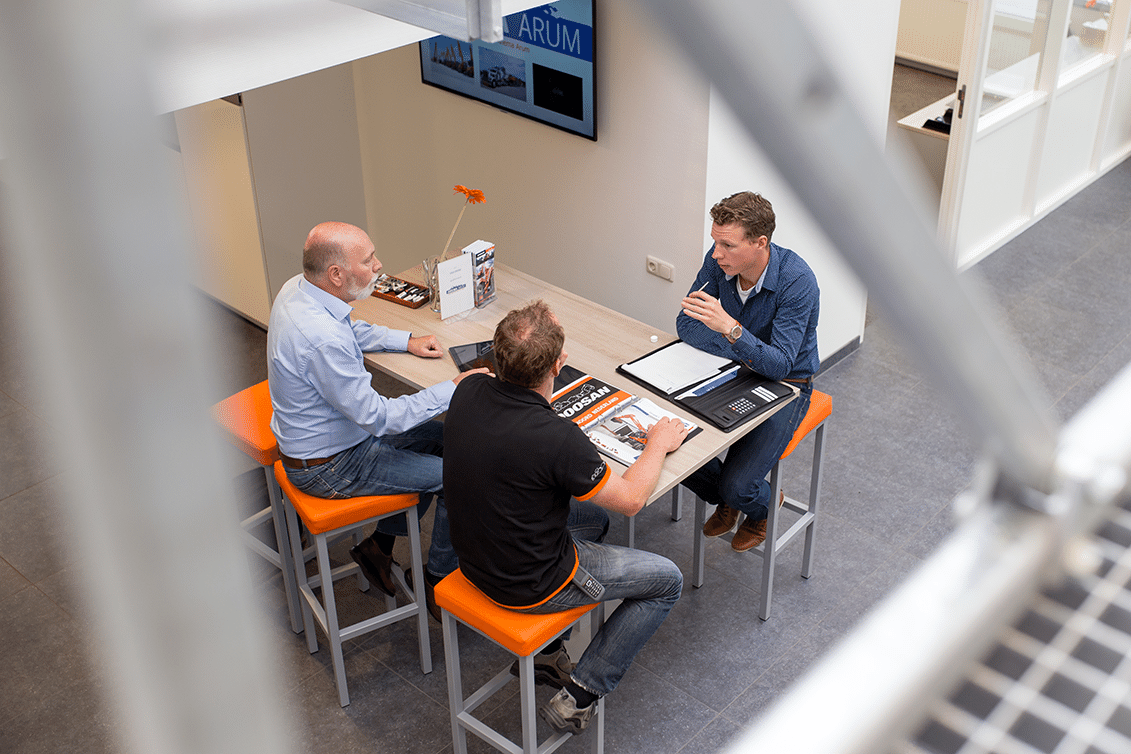 drie mannen zitten aan een tafel en hebben zakelijk overleg